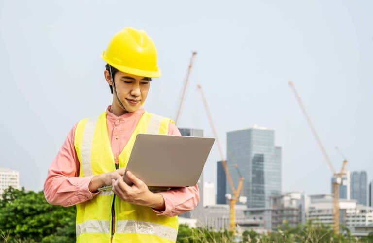 California Government Facility ADA Checklist: Avoid Fines & Get Fully Compliant 6 A construction worker wearing safety gear uses a laptop on-site during ADA compliance upgrades at a California government facility