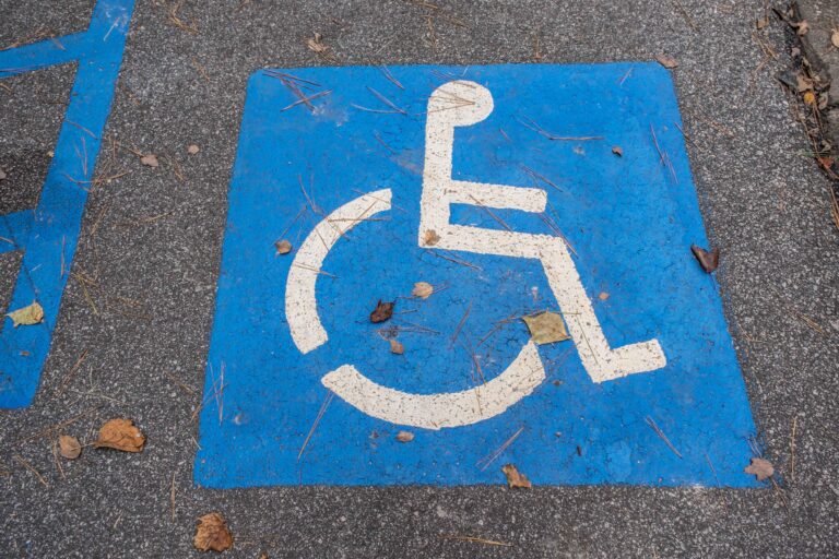 Faded blue access aisle symbol in a van-accessible parking space with visible wear