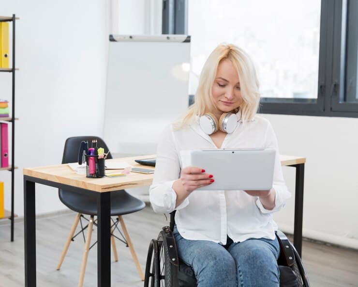 California Government Facility ADA Checklist: Avoid Fines & Get Fully Compliant 7 A woman in a wheelchair working on a tablet, representing challenges faced in non-ADA-compliant California government offices