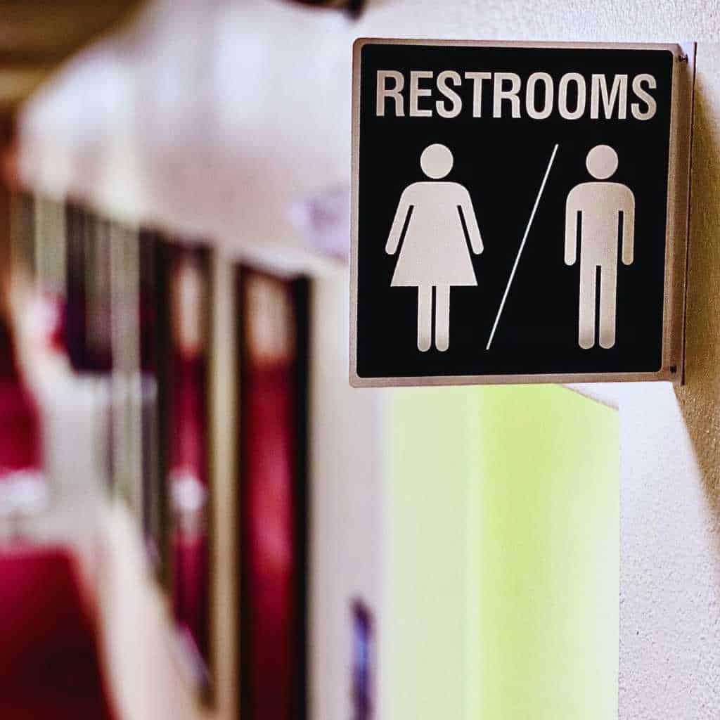 Make Your San Diego Restroom ADA Compliant | Step-by-Step Upgrade Guide 4 A wall-mounted restroom sign with male and female symbols and no tactile or Braille features, highlighting a common signage issue that fails to meet California Title 24 and ADA requirements for accessible restrooms.