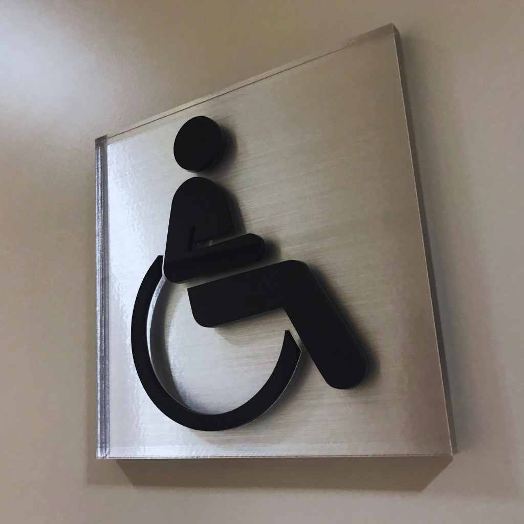 Wall-mounted accessibility symbol showing a wheelchair icon, used in California buildings to mark compliant entrances, restrooms, and public spaces during a CASp inspection review.