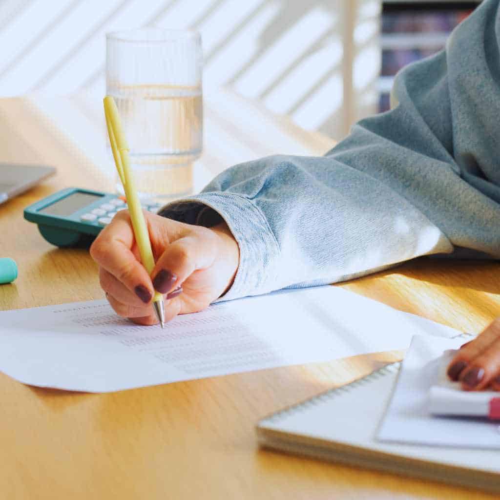 A person reviewing paperwork with a pen and calculator on the table, representing how California business owners prepare documents and estimate CASp inspection costs.