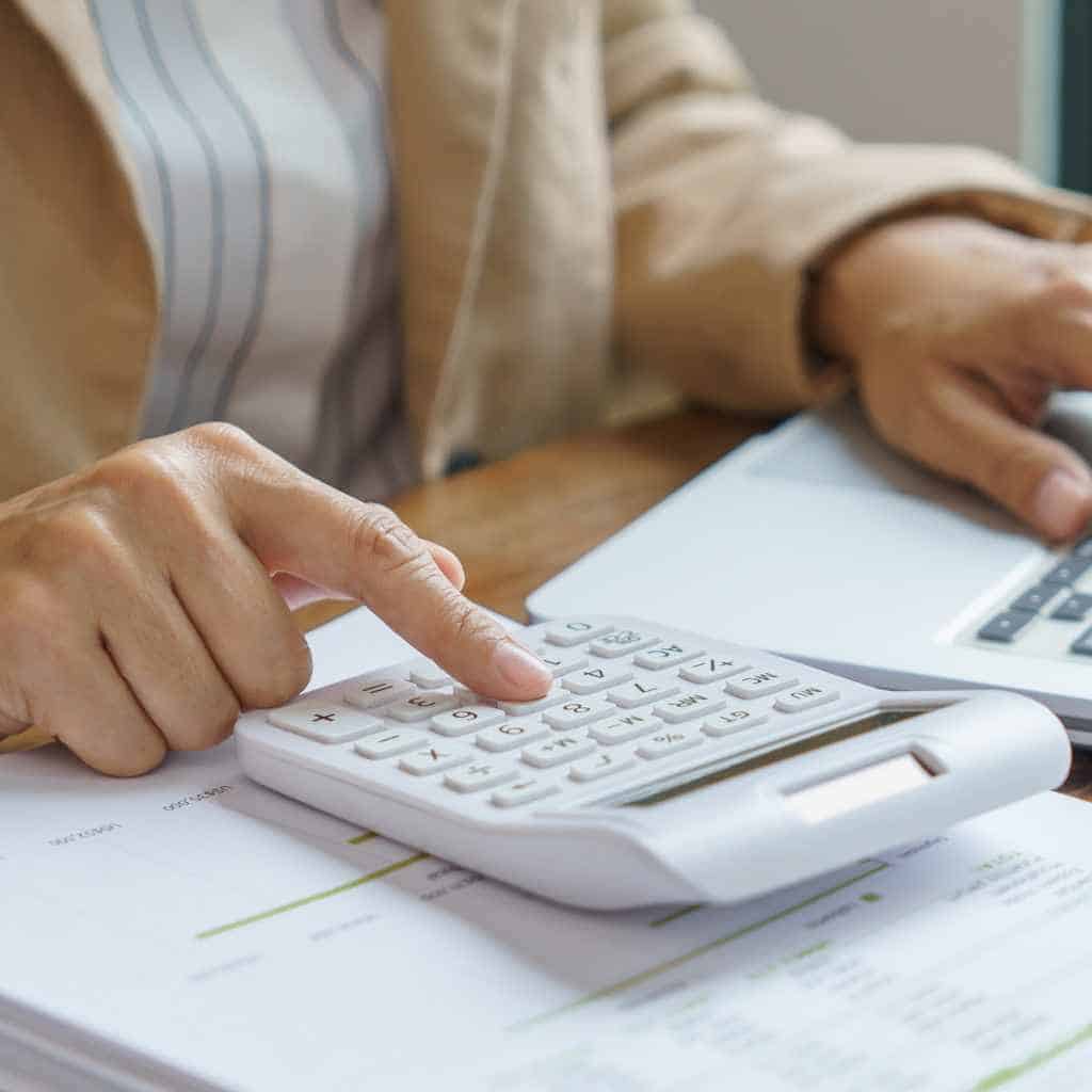 Person reviewing CASp inspection expenses with a calculator and paperwork, representing how California accessibility audit prices are calculated under ADA and Title 24 requirements.