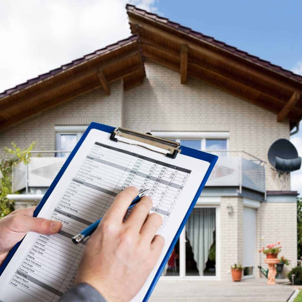 Hands reviewing a detailed property checklist on a clipboard outside a commercial building, illustrating the documentation and measurement steps involved in a California CASp inspection and cost evaluation.
